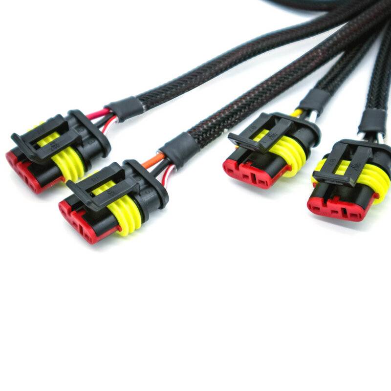 Vier Elektrostecker mit schwarzen Gehäusen, gelben Dichtungen und roten Anschlüssen, befestigt an schwarzen geflochtenen Kabeln, die in einer Fächeranordnung angeordnet sind.