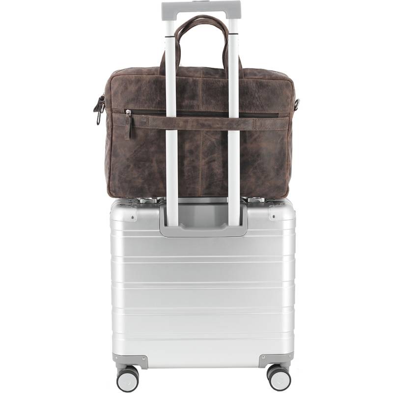 Eine braune Ledertasche, die sicher am Griff eines silbernen Hartschalenkoffers mit vier Rollen befestigt ist, vor einem schlichten Hintergrund.