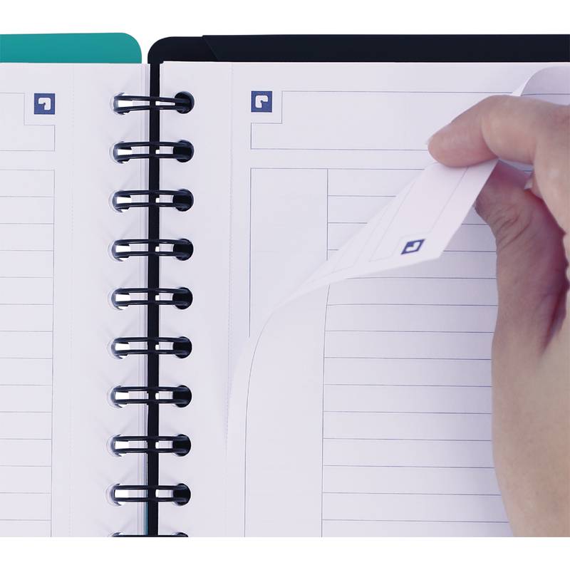 Eine Hand schlägt eine Seite in einem offenen Spiralblock um und zeigt liniertes Papier mit einem kleinen Quadrat-Symbol in der Ecke jeder Seite.