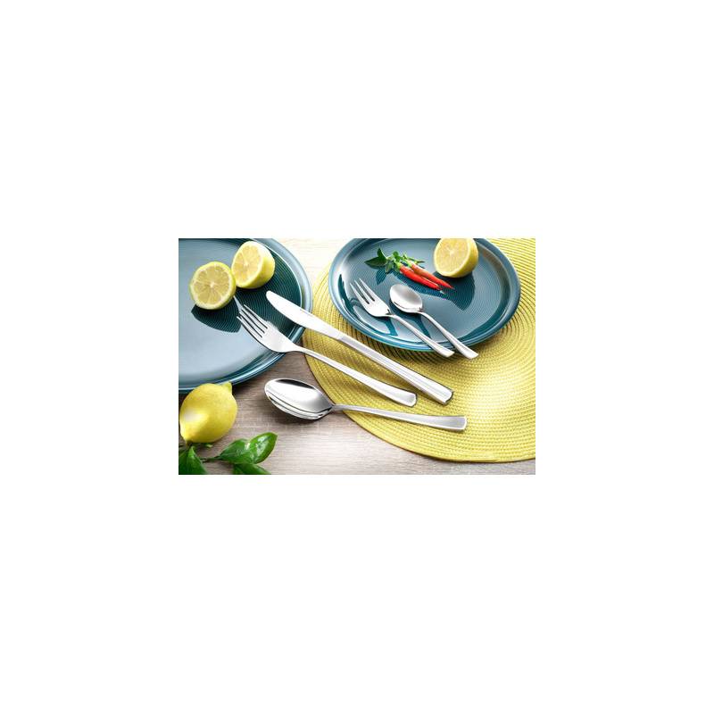 Blaue Teller mit silbernem Besteck, Messer und Löffeln auf einer gelben Tischdecke, angeordnet mit Zitronenhälften, einer ganzen Zitrone und roten Chilischoten.