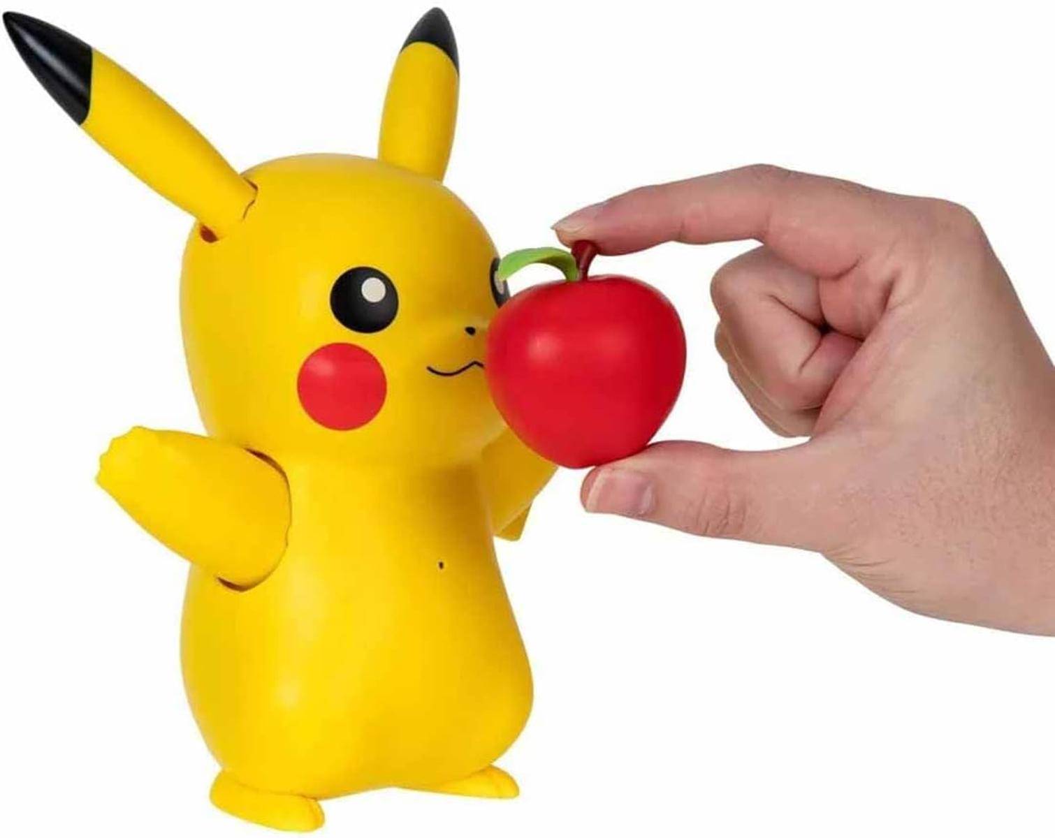Ein gelbes Pikachu-Spielzeug, das sich einer Hand entgegenstreckt, die einen roten Apfel hält.