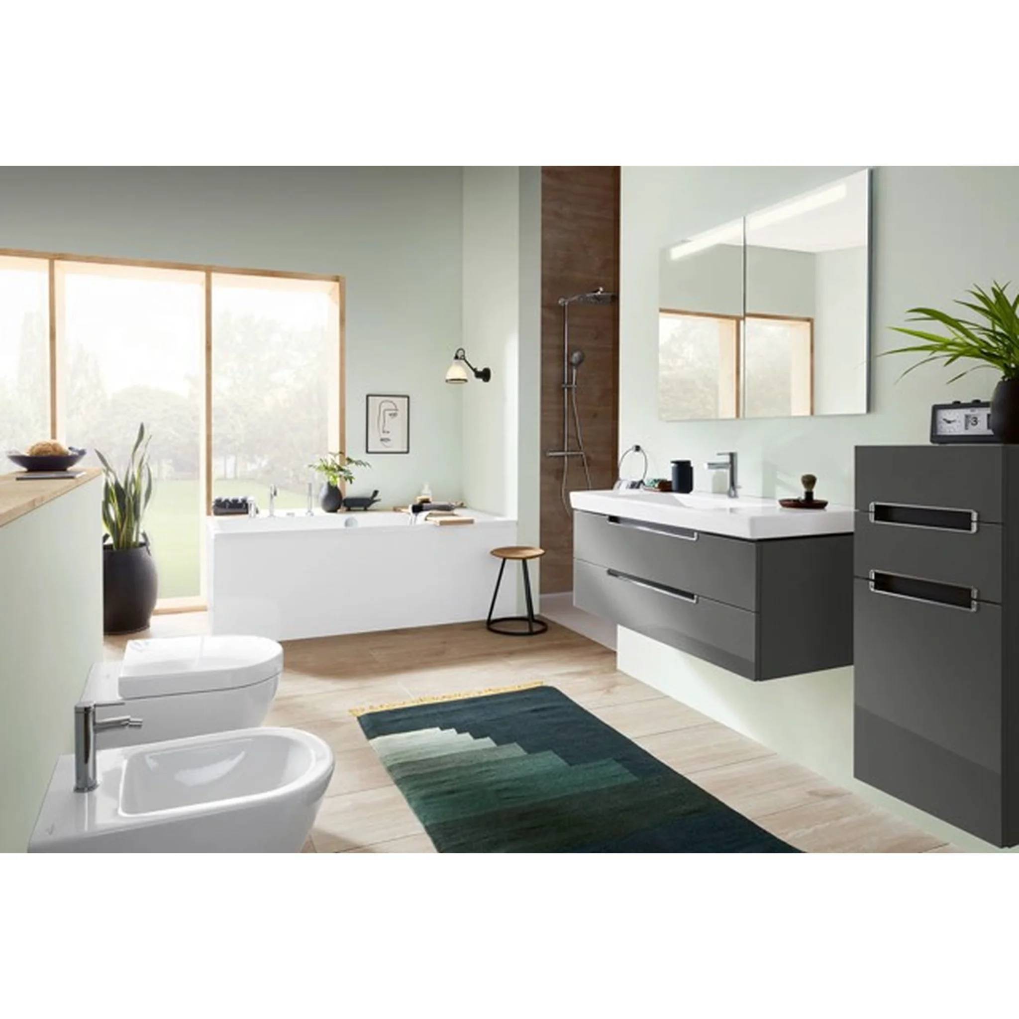 Modernes Badezimmer mit weißer Badewanne und Toilette, dunklem schwebendem Waschbecken und Schrank, großem Spiegel, begehbarer Dusche, Fenster und grünem Teppich