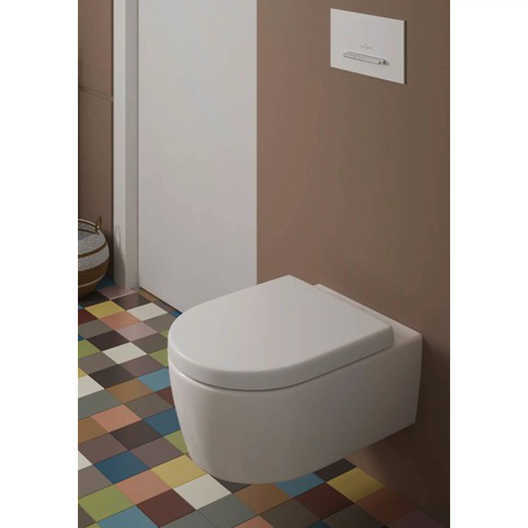 Modernes an der Wand montiertes Toilettenbecken in einem Badezimmer mit mehrfarbigem Schachbrettmuster-Fliesenbelag und neutralen braun-weißen Wänden.