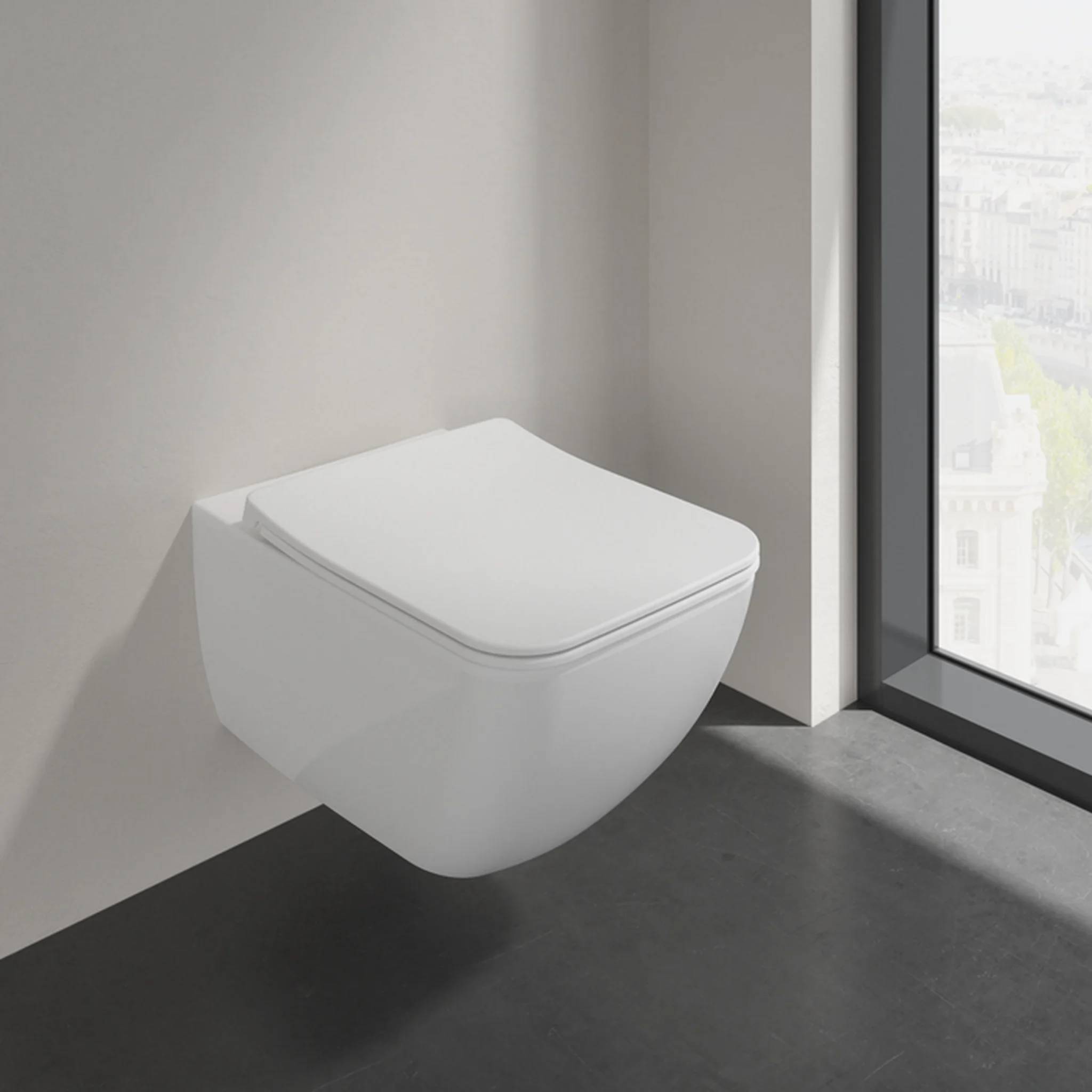 Minimalistische an der Wand montierte weiße Toilette neben einem raumhohen Fenster in einem modernen Badezimmer.