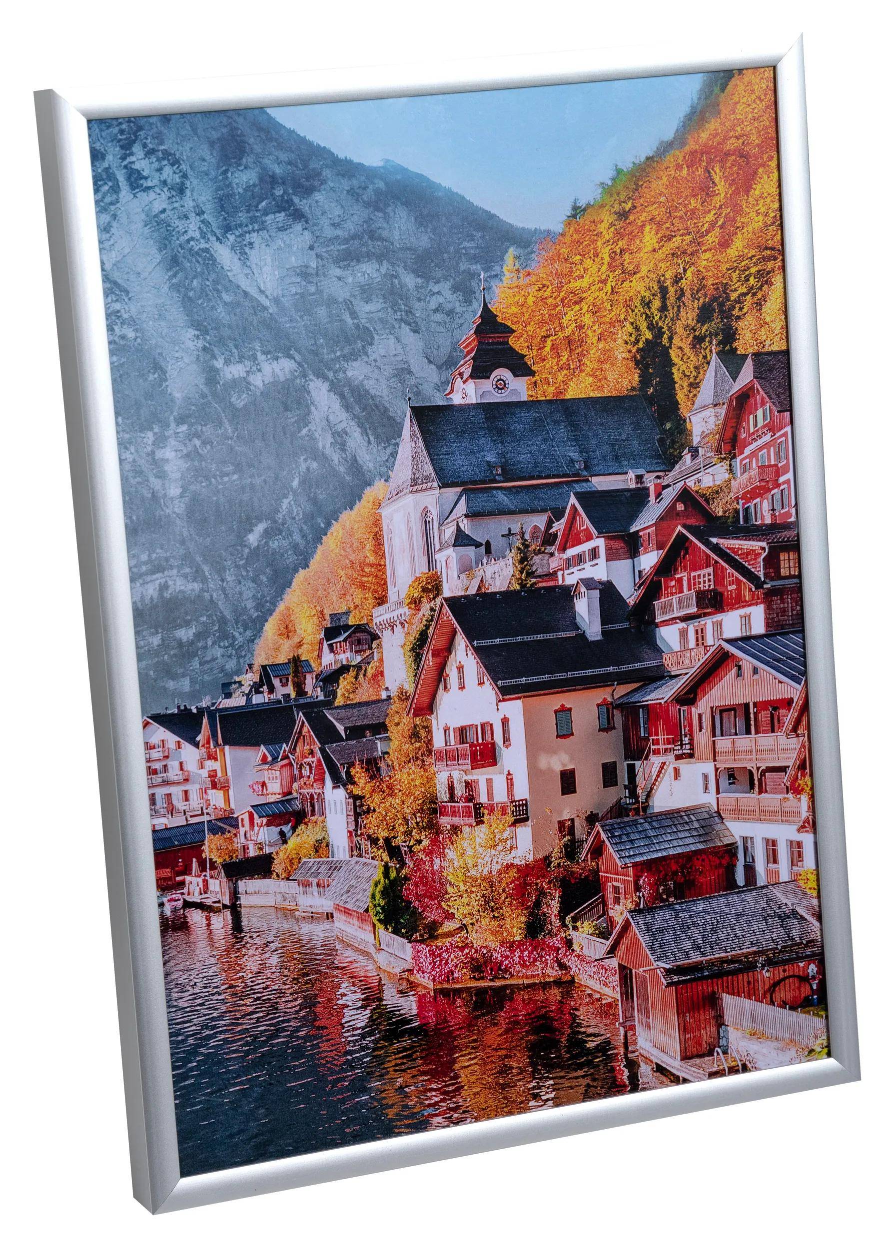 Malerische Aussicht auf das Dorf Hallstatt mit farbenfrohen Herbstbäumen, traditionellen Alpenhäusern und einer Kirche vor einer Bergkulisse.