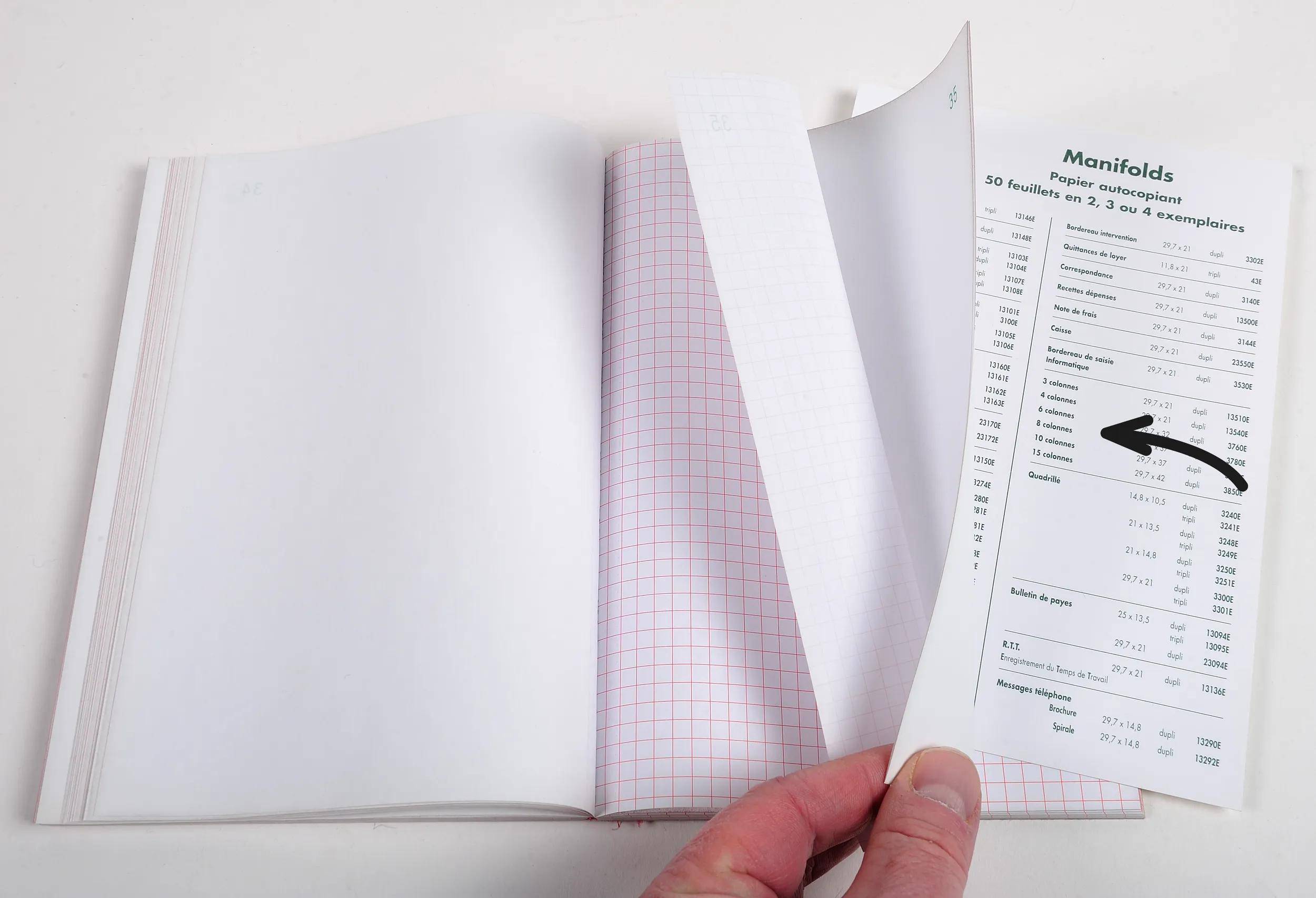 Eine Person blättert eine Seite in einem Notizbuch um. Die offene Seite zeigt ein Gittermuster, und die umgeblätterte Seite listet die Spezifikationen von „Papier Oxford