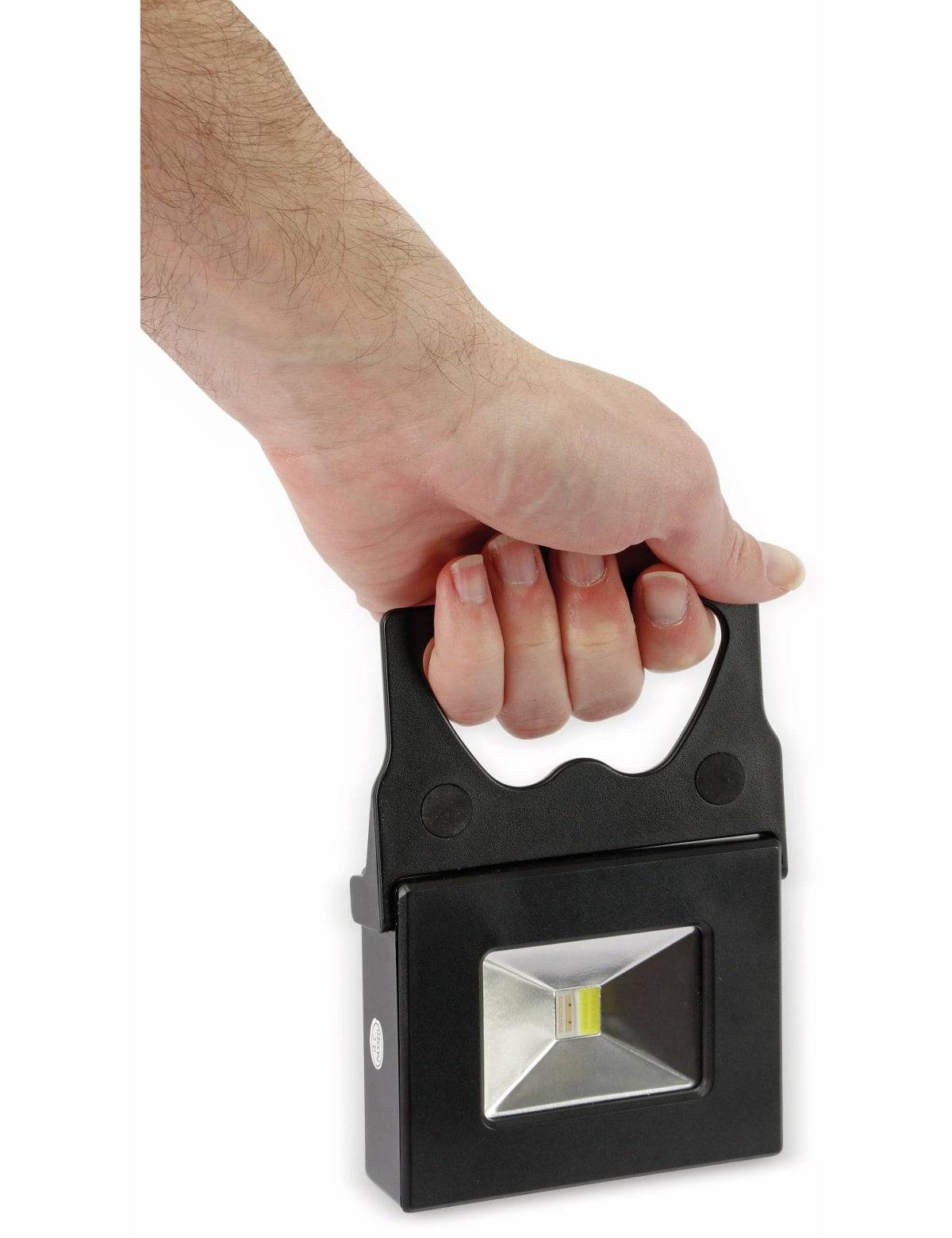 Eine Hand, die eine tragbare LED-Arbeitsleuchte hält, zeigt ihr kompaktes rechteckiges Design und das helles zentrales Licht.