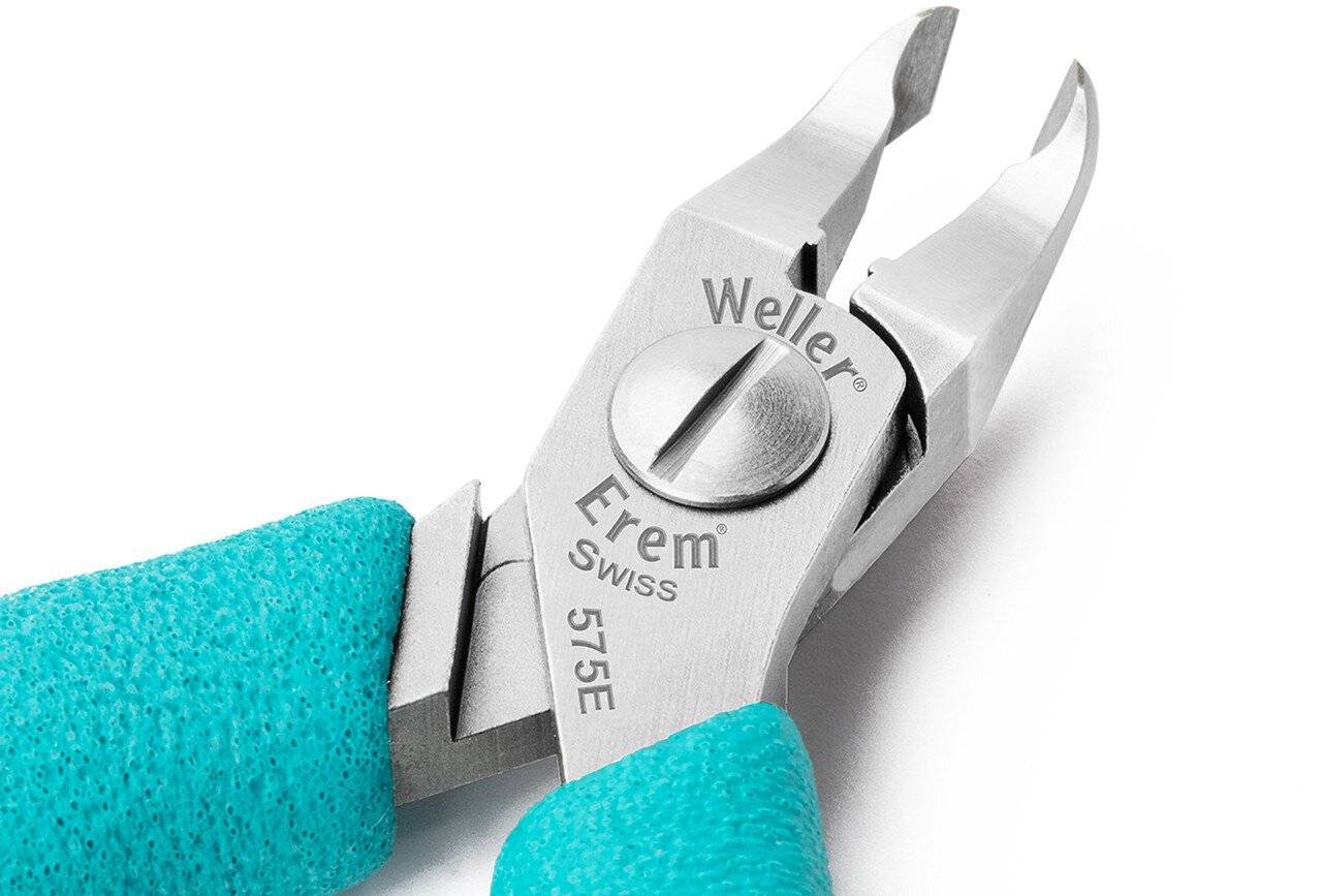 Nahaufnahme einer Hand mit türkisfarbenem Handschuh, die Edelstahl-Nagelknipser mit der Bezeichnung „Weller Erem Swiss 575E" gegen einen weißen Hintergrund hält.