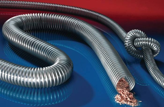 Nahaufnahme eines flexiblen Metallschutzschlauchs, teilweise aufgeschnitten, um Kupferkabel freizulegen, vor einem rot-blauen Verlaufshintergrund.