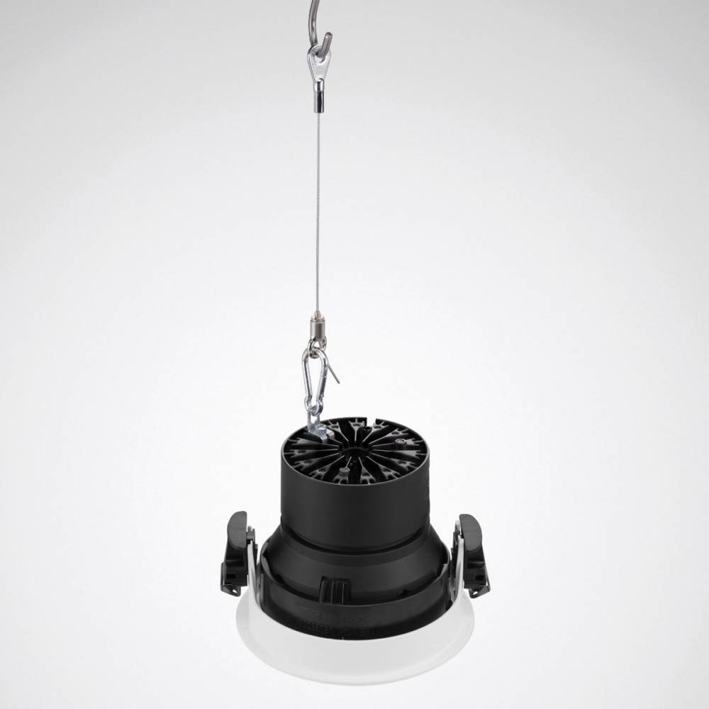 Eine Deckenleuchte, die an einem Kabel hängt, mit einem schwarzen Kühlkörper und einem weißen Diffusor, die vor einem einfarbigen Hintergrund positioniert ist.