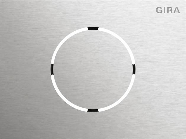 Ein schlankes, kreisförmiges Design mit einer gebürsteten Metalloberfläche und vier gleichmäßig entlang des Kreisrands verteilten schwarzen Segmenten auf einem metallischen Hintergrund.