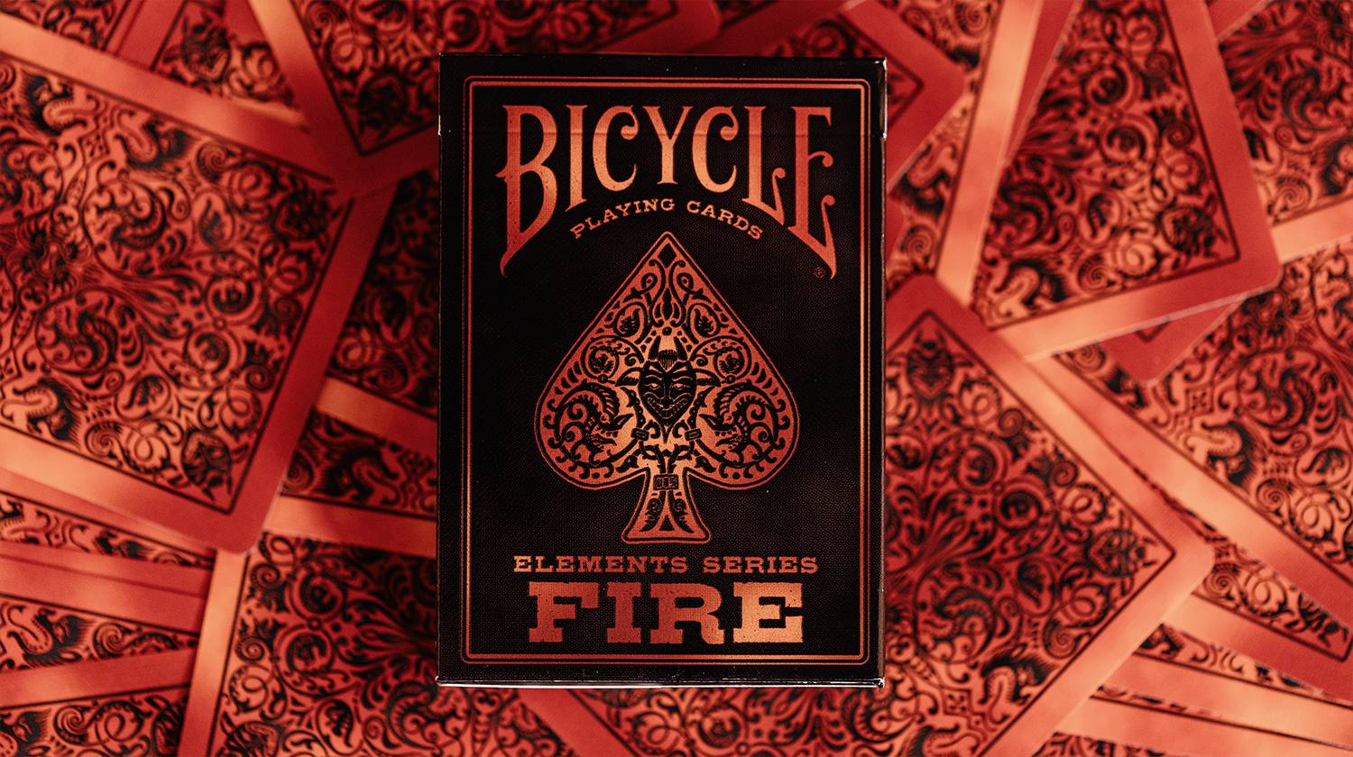 Eine Bicycle-Spielkarten-'Elements Series Fire'-Schachteln zentriert auf einem Hintergrund von roten gemusterten Kartenrückseiten.