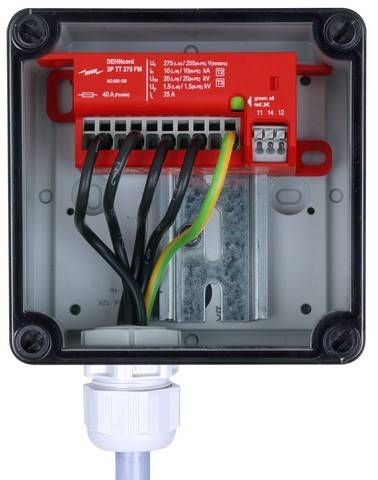 Eine Nahaufnahme einer elektrischen Verteilerdose mit einem roten Überspannungsschutzelement, das mit mehreren Kabeln in verschiedenen Farben verbunden ist.