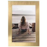 Gerahmtes Foto einer Frau, die auf einem Holzsteg sitzt und einem ruhigen See zugewandt ist, aus der Perspektive von hinten betrachtet.