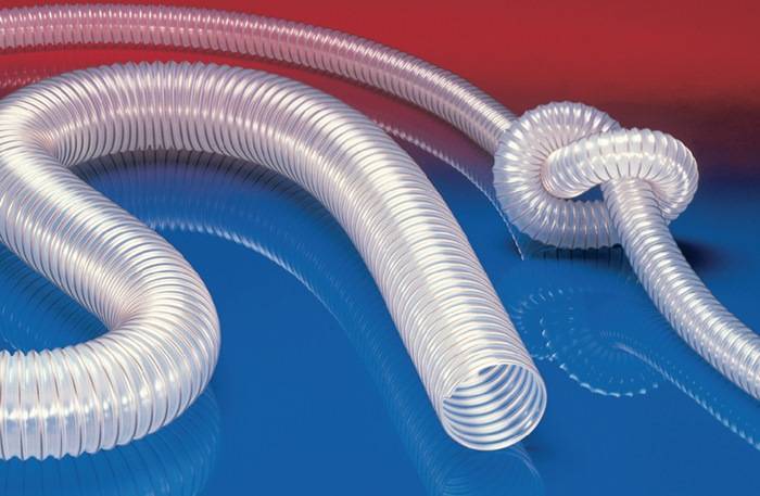 Ein gekräuselter, transparenter Schlauch ist auf einer rot-blauen Oberfläche angeordnet. Der Schlauch wirkt flexibel und hebt seine geschwungene Form vor dem kontrastierenden Farbhintergrund hervor.