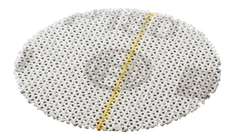 Ein kreisförmiges Netzimplantat mit einer gelben Linie in der Mitte, wahrscheinlich für medizinische Eingriffe wie Hernienreparaturen verwendet.