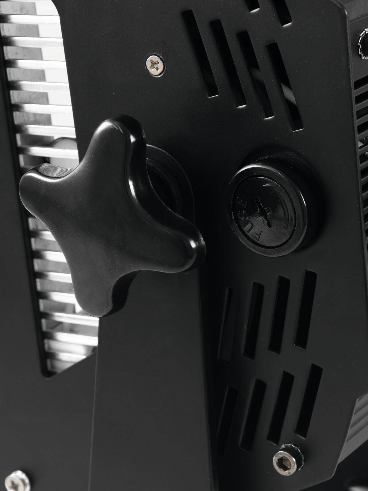 Nahaufnahme eines schwarzen mechanischen Knopfes auf einer texturierten Metalloberfläche, mit industriellem Design, vertikalen Schlitzen und einem kreisförmigen Indikator.