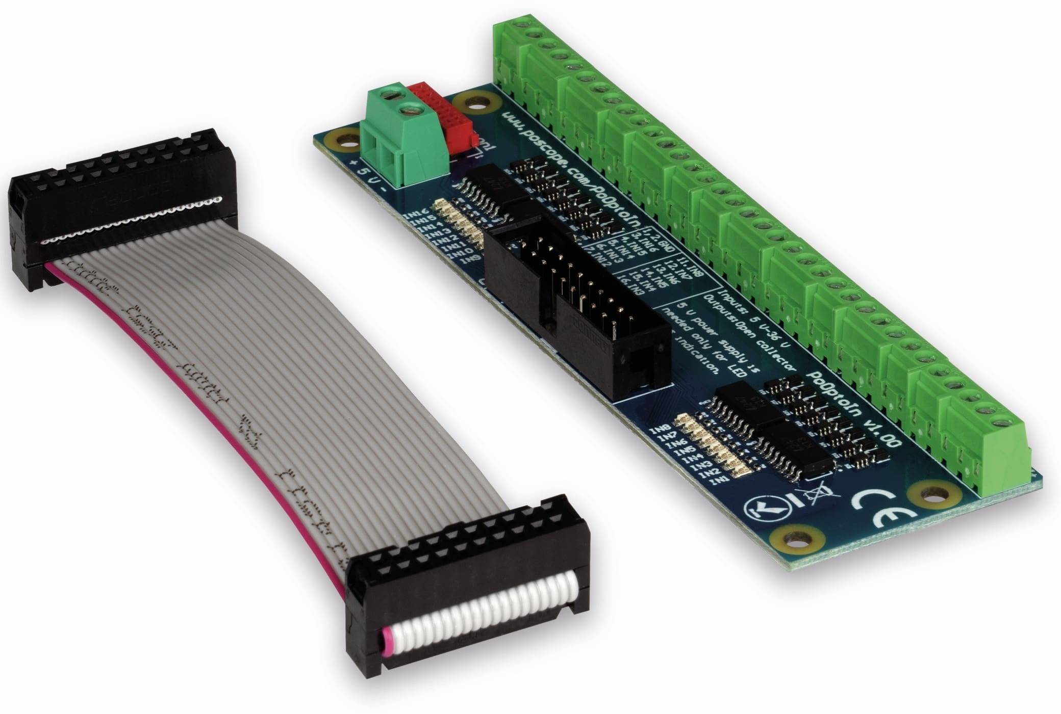 Grüne Leiterplatte mit mehreren grünen Klemmenblöcken neben einem grauen Flachbandkabel mit einem schwarzen Anschluss.