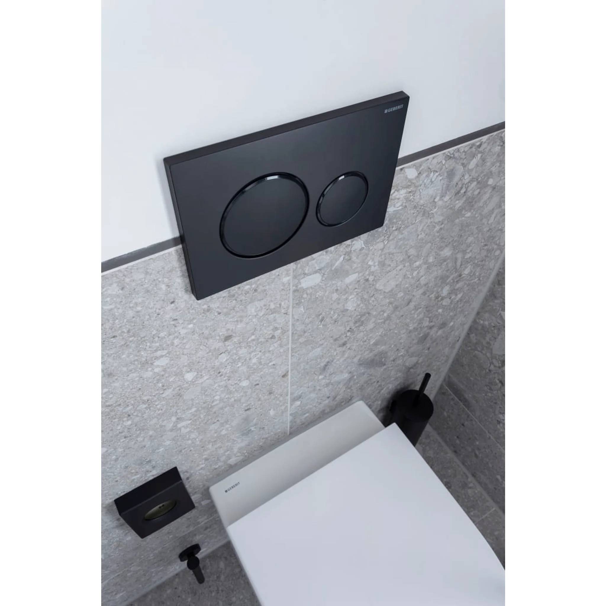 Modernes wandhängendes WC mit verborgenem schwarzem Doppelspülsystem in einer gefliesten Toilettenkabine.