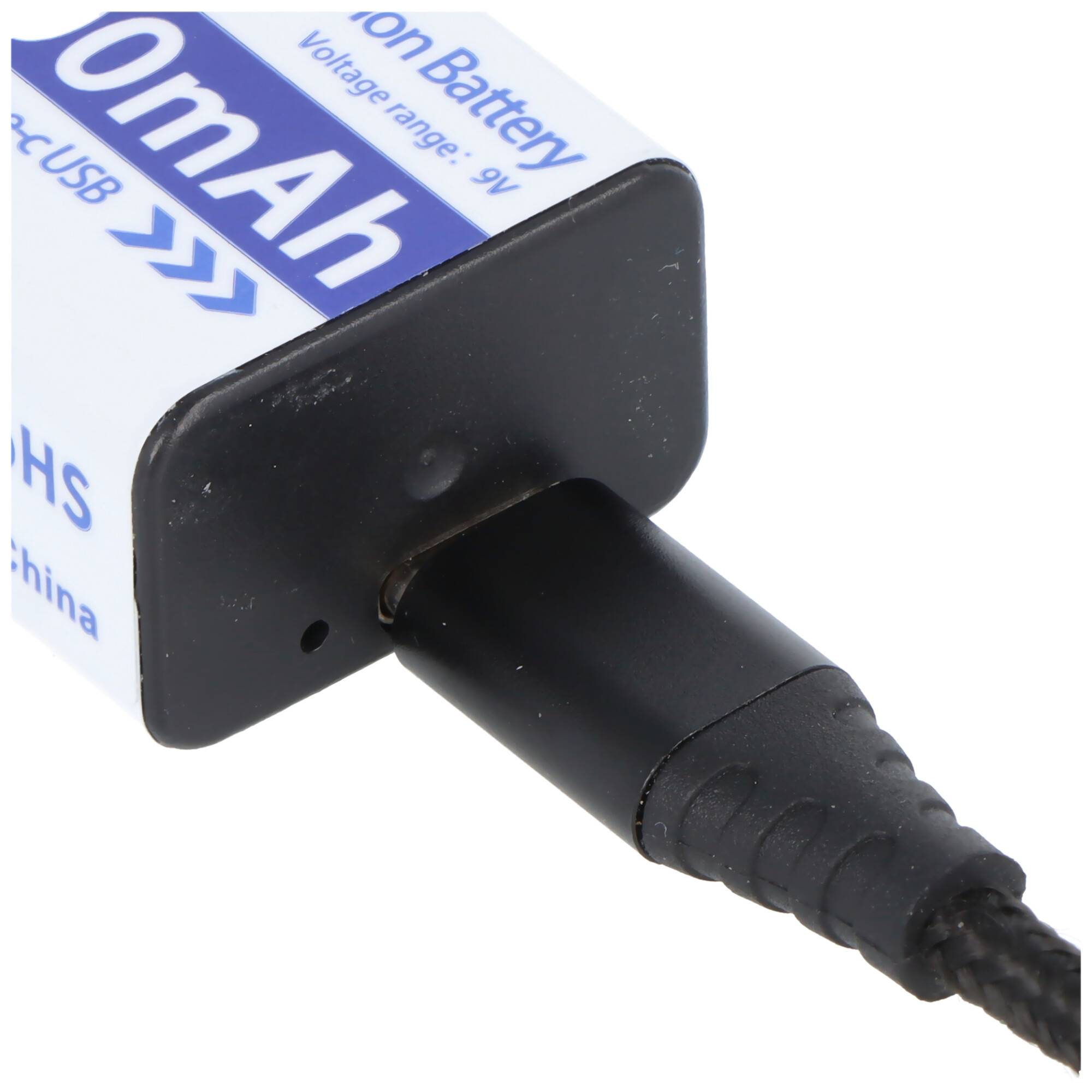Nahaufnahme einer Batterie mit einem schwarzen Stromkabel, das in ihren Anschluss eingesteckt ist, wobei ein drahtgebundener Batteriestecker zu sehen ist.
