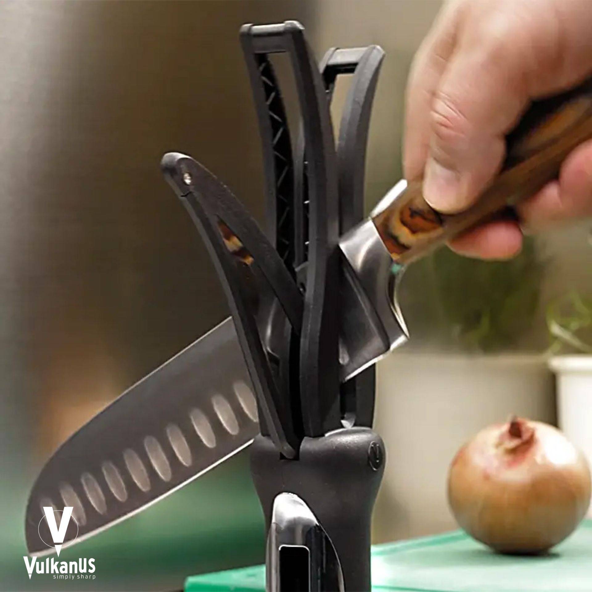 Eine Hand schärft ein Küchenmesser mit einem Vulkanus-Messerschärfer auf einer Arbeitsplatte mit einer Zwiebel im Hintergrund.