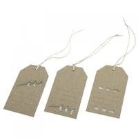 Drei braune Papiergeschenkanhänger mit weißen Schnüren, jeder mit kleinen metallischen Nieten oder Clips versehen.
