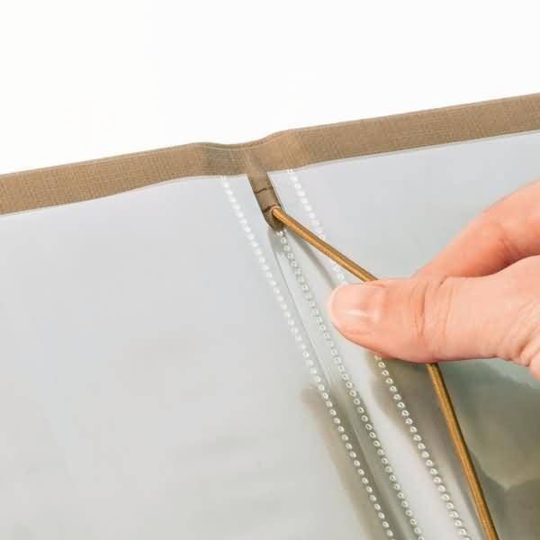 Nahaufnahme einer Hand, die eine Schnur durch eine Naht oder einen Reißverschluss an einer durchsichtigen Plastikabdeckung einfädelt oder verstellt.