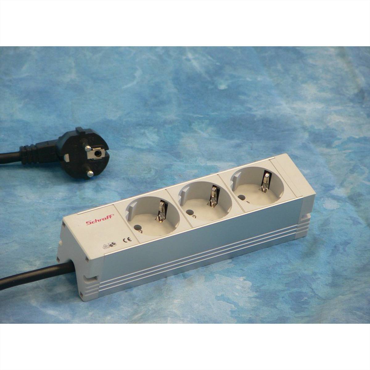 Steckdosenleiste mit drei Steckdosen und angeschlossenem Stecker auf einer blauen Oberfläche, die eine Schroff-Marken-Stromverlängerung zeigt.