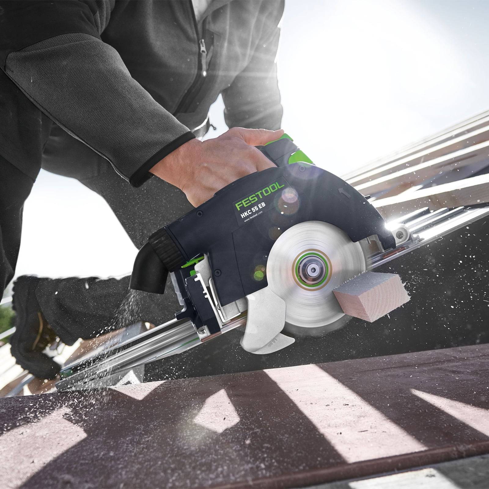 Eine Person benutzt eine Festool Kreissäge, um einen Holzbalken auf einem Dach zu schneiden und dabei Präzision und Kraft in einem Baustellensetting zu demonstrieren.