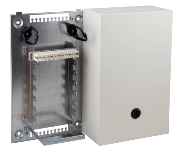 Eine offene Metall-Stromverteilerdose mit freigelegten Anschlüssen, an einer Wand montiert, neben einer geschlossenen weißen Box mit einem runden Schloss.