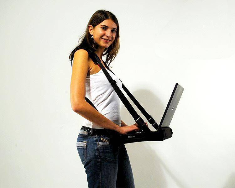 Eine Person steht und tippt auf einem Laptop, der mittels eines Geschirrs von ihren Schultern getragen wird, wodurch eine Nutzung ohne Hände ermöglicht wird.