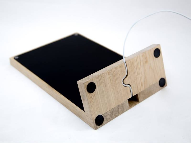 Ein Tablet-Ständer aus Holz mit einem Ladekabelschlitz und rutschfesten schwarzen Auflagen am Boden.