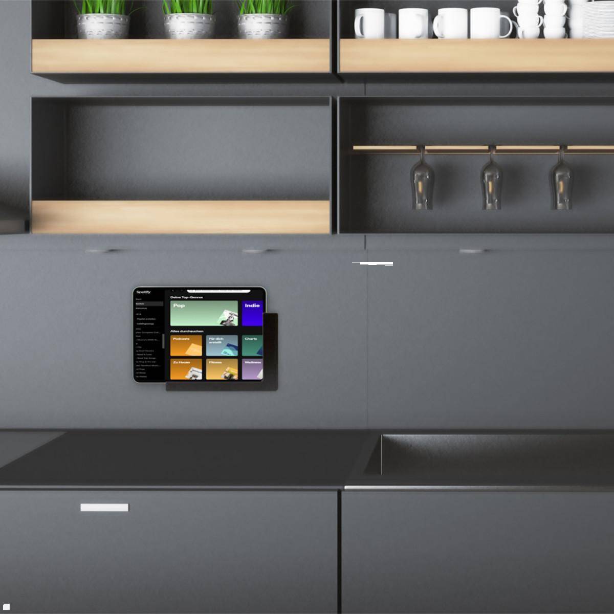 Eine moderne Küchenwand zeigt glatte Schränke mit Pflanzen und Tassen darauf. Ein Tablet-Display zeigt Smart-Home-Steuerungen neben einer Küchenarbeitsplatte.