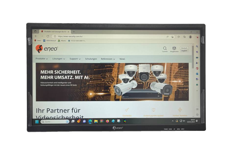 Ein Laptop zeigt die Startseite der eneo-Website mit einem sicherheitsthematischen Banner, das zwei Roboter und die deutsche Überschrift „MEHR SICHERHEIT. MEHR UMSATZ. MIT AI.