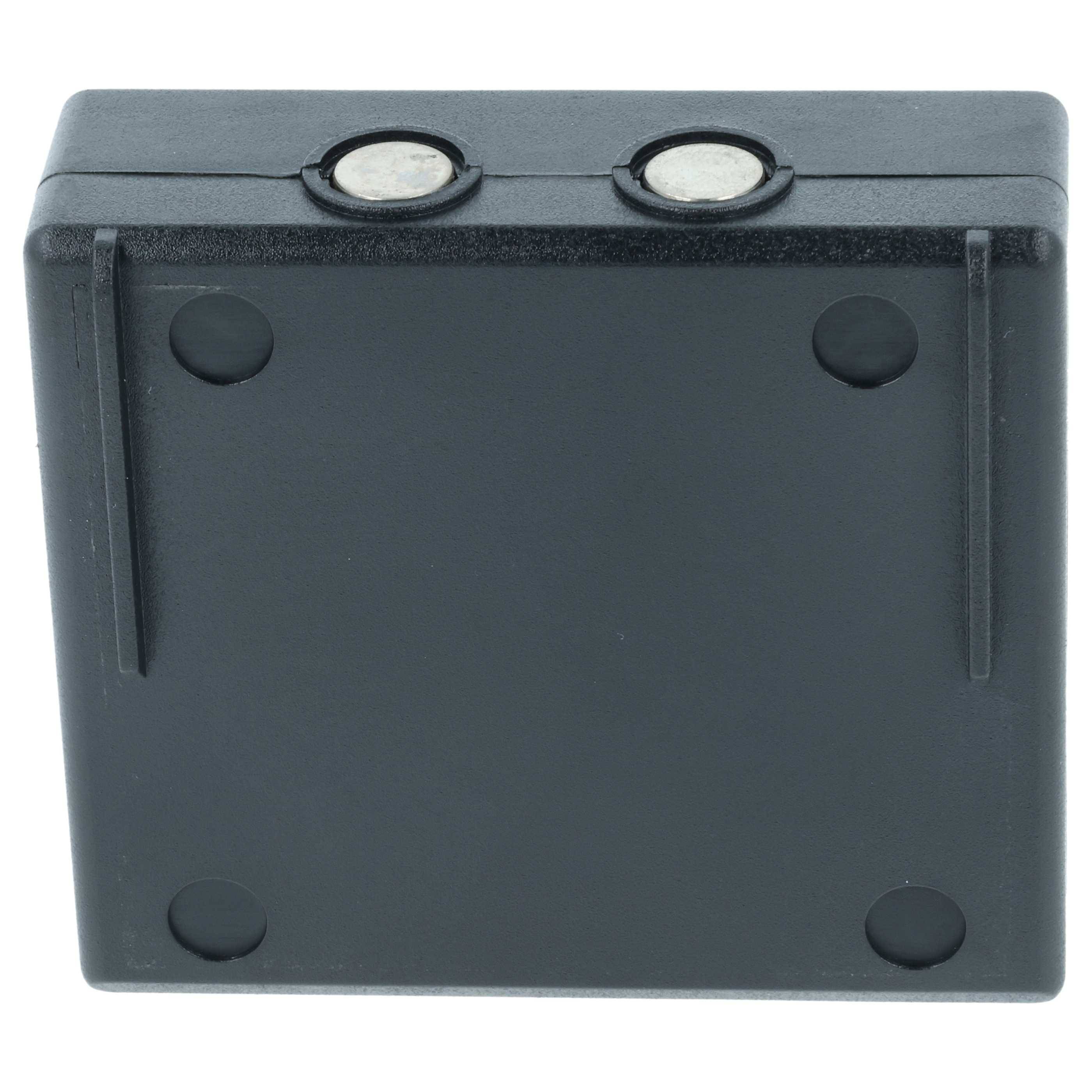 Eine schwarze Plastikquadratbox mit zwei runden, metallischen Kontaktpunkten oben und vier kreisförmigen Vertiefungen auf der Oberfläche, höchstwahrscheinlich ein Batteriefach.