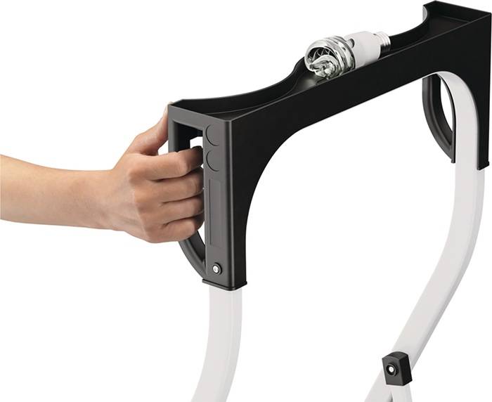 Eine Hand hält ein schwarzes, rahmengestütztes Gerät, das an einem Fahrrad befestigt ist, mit sichtbaren Schläuchen und einer Glühbirne oben.