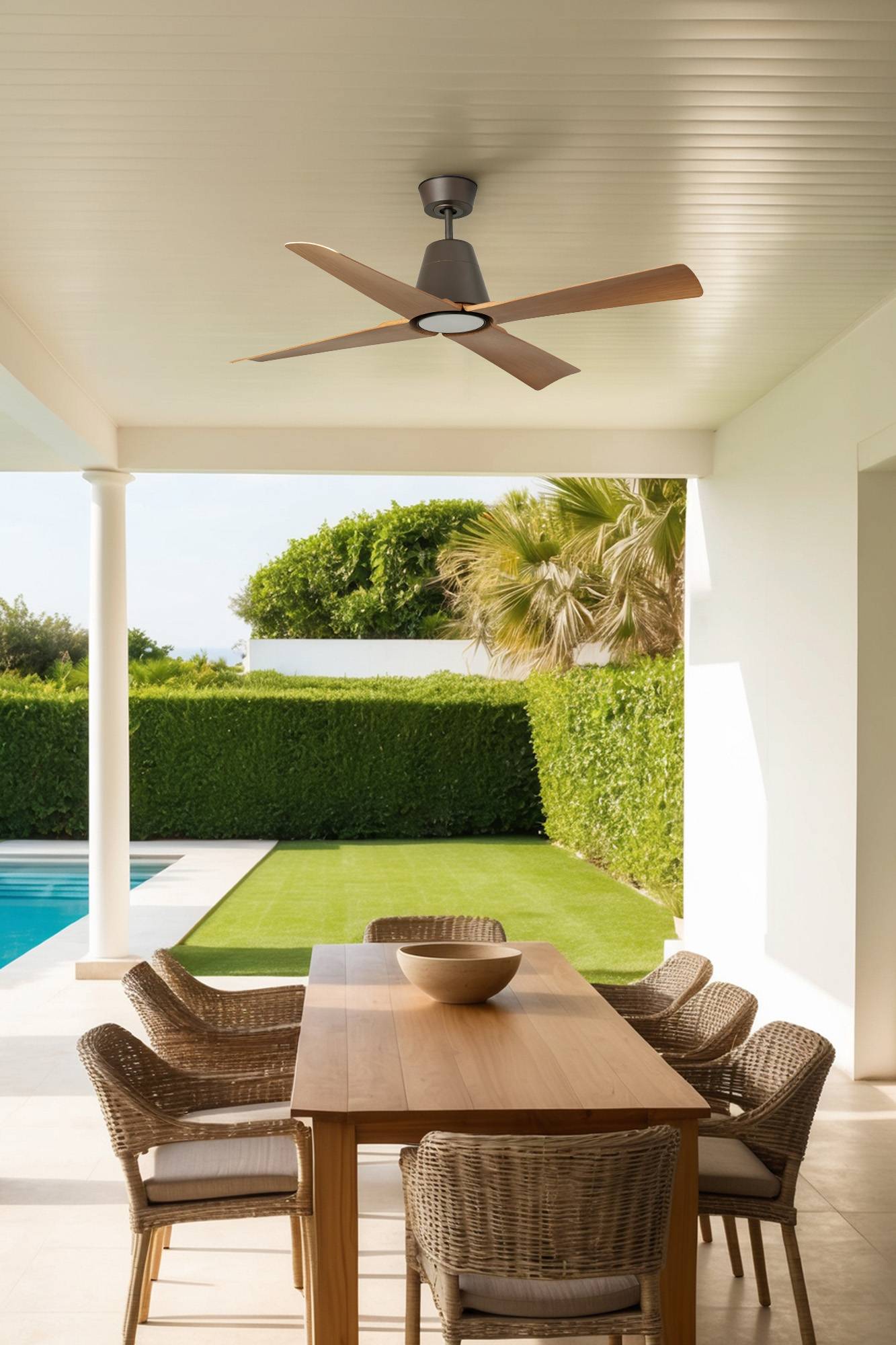 Überdachter Terrassenbereich zum Essen mit Holztisch und Rattanstühlen mit Blick auf einen Pool, einen gepflegten Rasen und einen Garten.