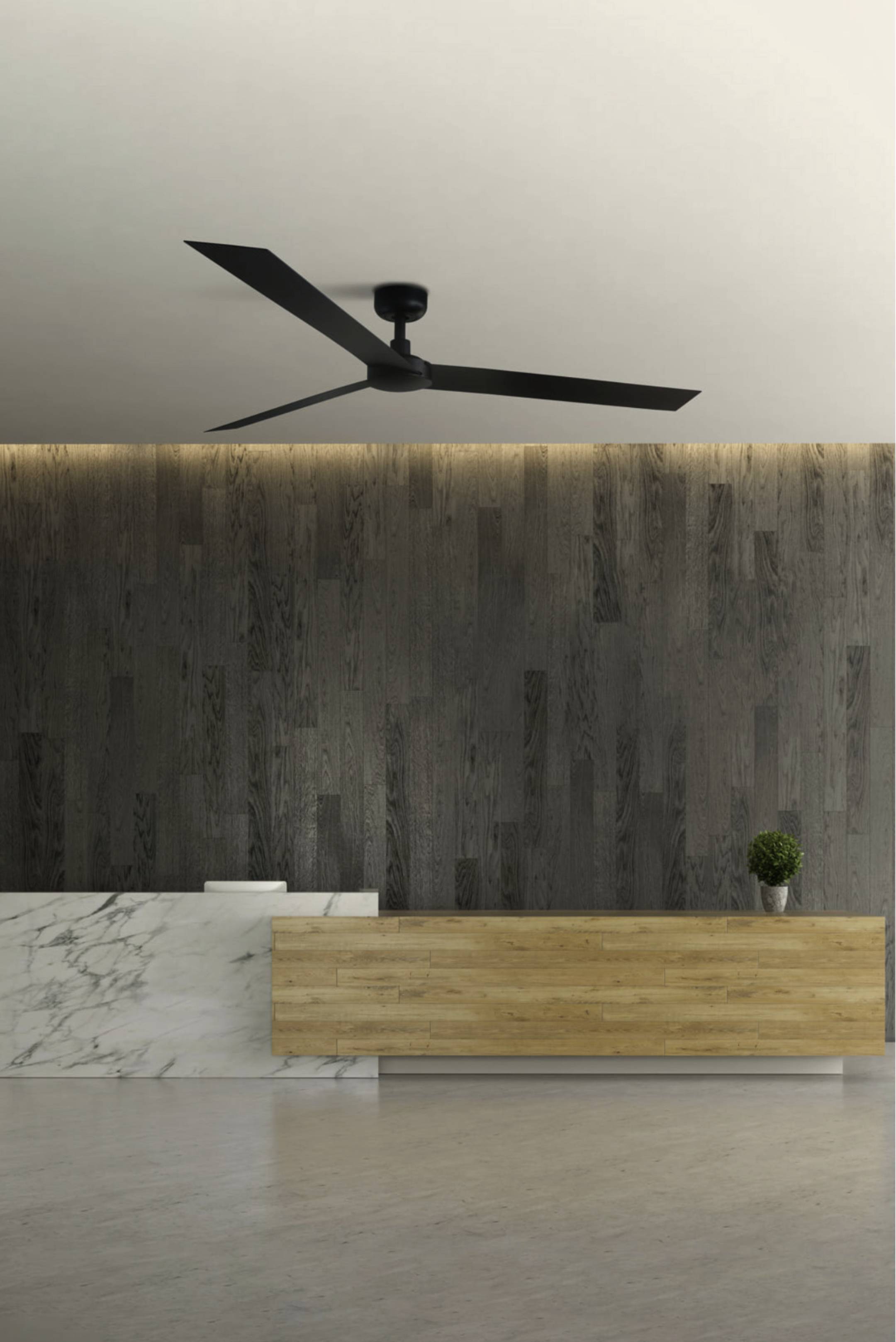 Moderner Empfangsbereich mit holzverkleideter Wand, Marmor- und Holztheke, einer kleinen Pflanze und einem großen schwarzen Deckenventilator darüber.