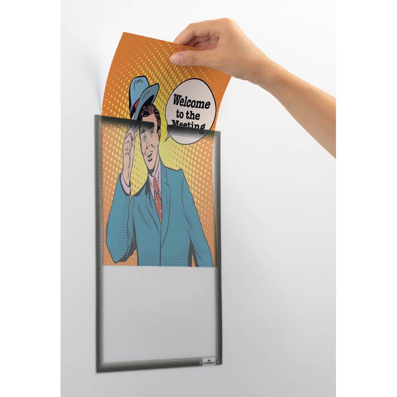 Eine Hand schiebt eine orange Karte in einen wandmontierten Rahmen. Die Karte zeigt einen Mann im Anzug, der Text lautet „Willkommen zur Besprechung