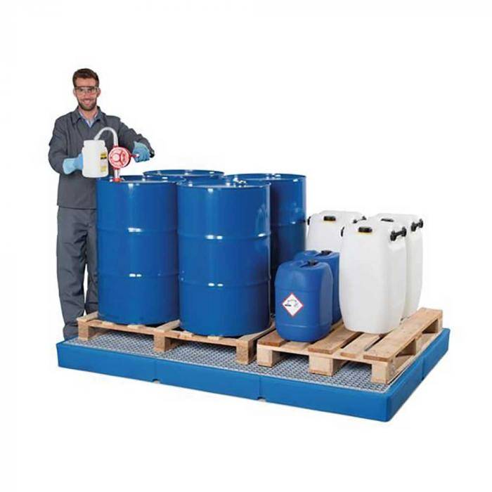 Arbeiter in Schutzkleidung steht neben Paletten mit großen blauen und weißen Chemikalienfässern und Kanistern auf einer Auffangwanne.