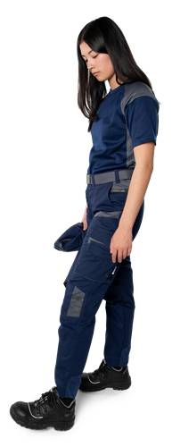Eine Person in einer blauen Uniform mit dunklen Akzenten, die in Seitenansicht steht und Arbeitskleidung präsentiert.