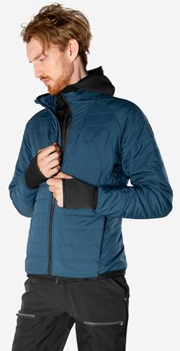 Eine Person trägt eine blaue, isolierte Jacke und hält dabei den Kragen. Die Jacke hat einen Reißverschluss vorne und eine schwarze Innenschicht, die durchscheint.
