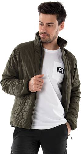 Eine Person, die eine dunkelgrüne gesteppte Jacke über einem weißen T-Shirt mit einem Logo auf der Tasche trägt.