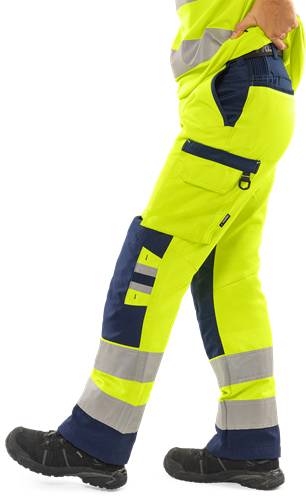 Eine Person, die eine helle gelbe und dunkel blaue Sicherheitsarbeitshose mit reflektierenden Streifen trägt, was darauf hindeutet, dass sie für eine Baustelle oder industrielle Umgebung bereit ist.