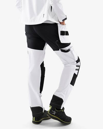 Eine Person trägt schwarze und weiße Sporthosen mit neongrün abgesetzten Schuhen und steht mit einem Bein leicht nach vorne gestellt.