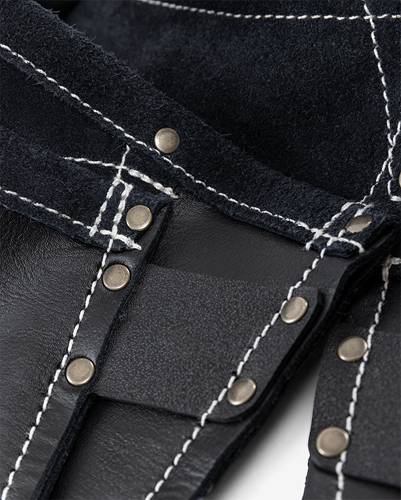 Nahaufnahme von schwarzem Leder mit weißen Nähten und metallischen Nieten, die das Handwerk und die Details der Verarbeitung für Bekleidung oder Accessoires hervorheben.