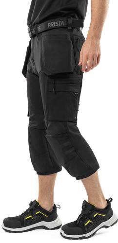 Cargoshorts mit mehreren Taschen, von einer Person vor einem schwarzen Hintergrund getragen.