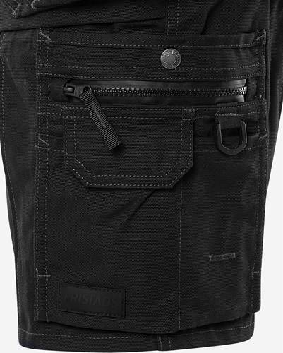 Detailaufnahme einer schwarzen, strapazierfähigen Stofftasche an einer Arbeitshose mit Reißverschluss und Druckknopf, versehen mit verstärkten Nähten und einer Gürtelschlaufe.