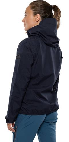 Eine Person in einer dunklen, kapuzenbekleideten Jacke, von hinten gesehen, vor einem schwarzen Hintergrund.