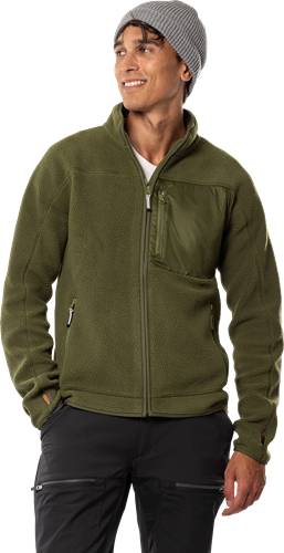 Eine Person, die eine grüne Fleecejacke mit einer Reißverschlusstasche auf der Brust und Seitentaschen trägt und damit eine lässige Outdoorbekleidung zur Schau stellt.
